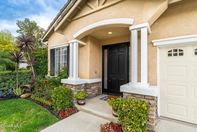 a front view of a house with a garden and trees