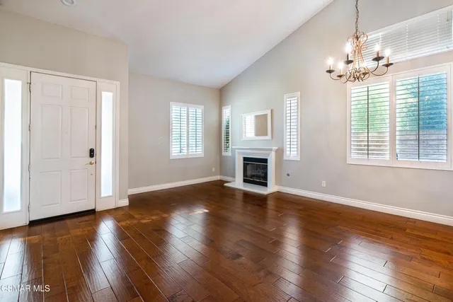 an empty room with wooden floor chandelier and windows