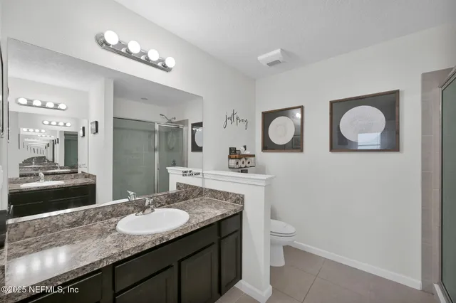 a bathroom with a granite countertop sink a toilet and a mirror