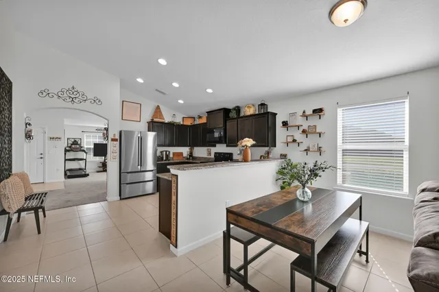a kitchen with stainless steel appliances kitchen island granite countertop a refrigerator and a dining table
