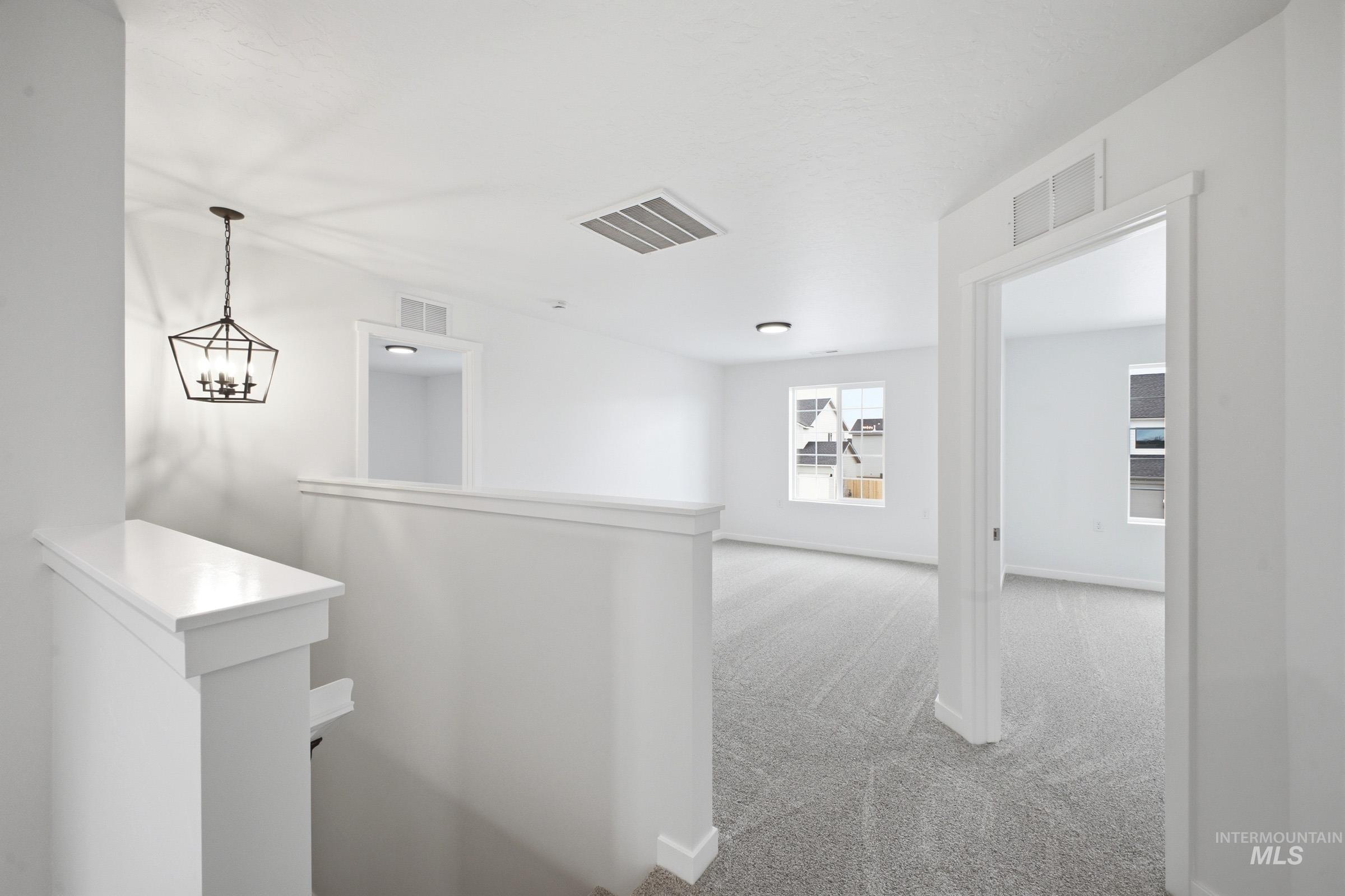 13724 Judson Street Caldwell, ID 83607 - Photo 12 of 23 Hallway with light colored carpet, hanging lights, and an upstairs landing