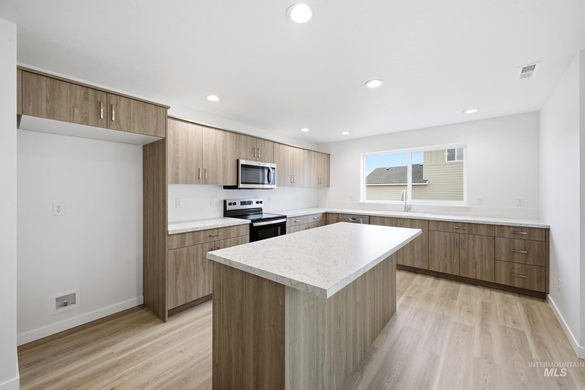 13724 Judson Street Caldwell, ID 83607 - Photo 3 of 23 Kitchen with a center island, electric stove, light countertops, light wood-style flooring, and stainless steel microwave
