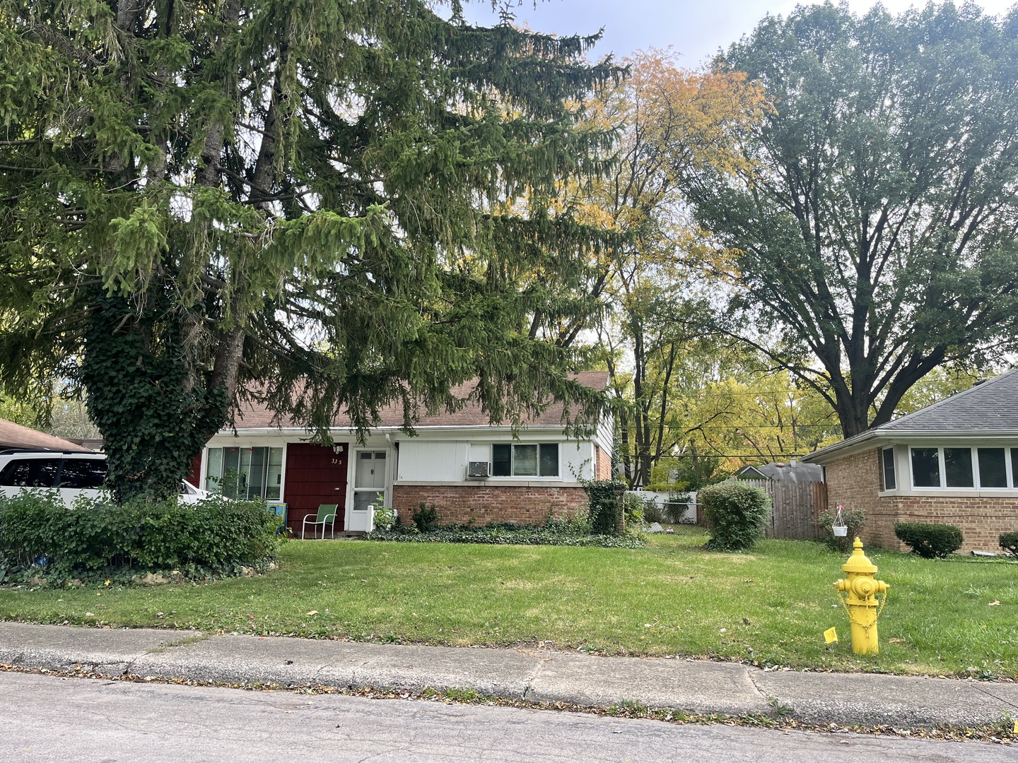a front view of a house with a garden and trees