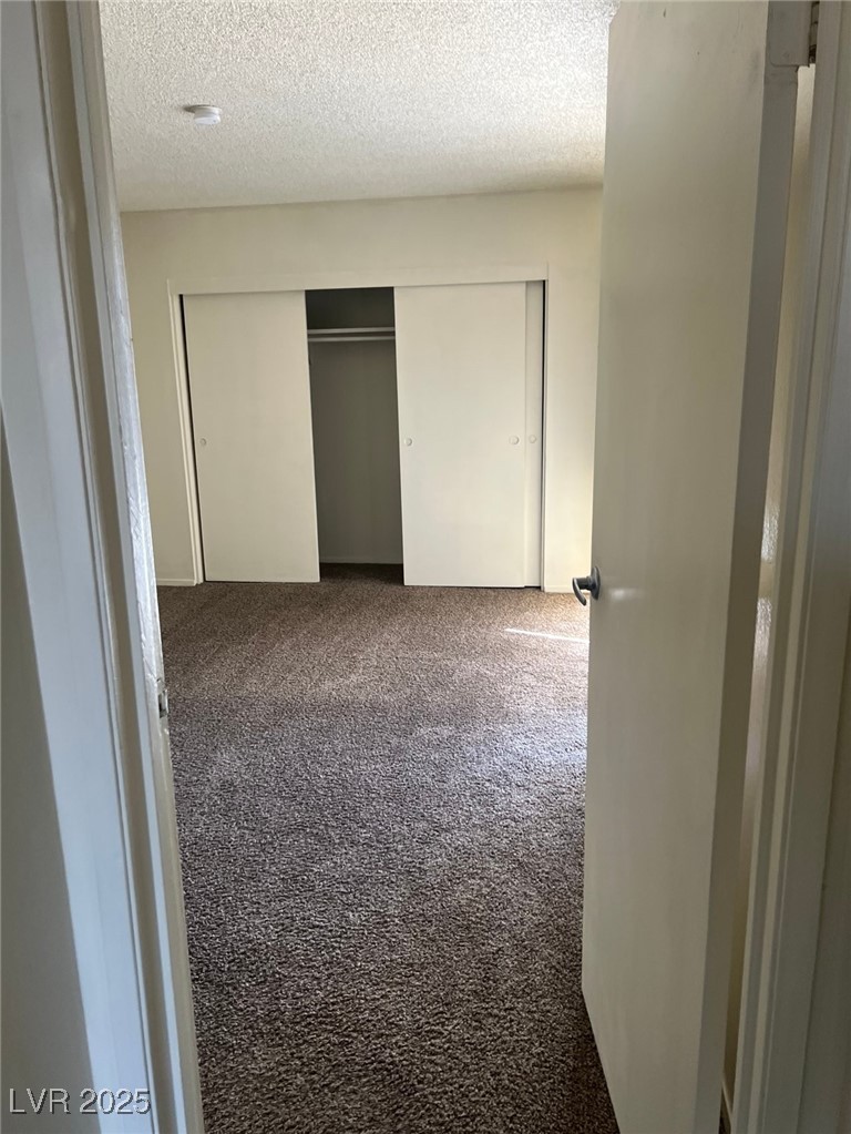 1388 East Desert Inn Road, Unit 1 Las Vegas, NV 89169 - Photo 15 of 17 Unfurnished bedroom with carpet flooring, a closet, and a textured ceiling
