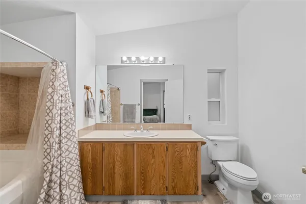 a bathroom with a granite countertop sink mirror vanity and toilet