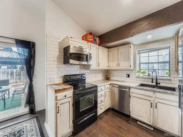 a kitchen with stainless steel appliances a sink dishwasher a stove top oven a refrigerator with grey cabinets and wooden floor