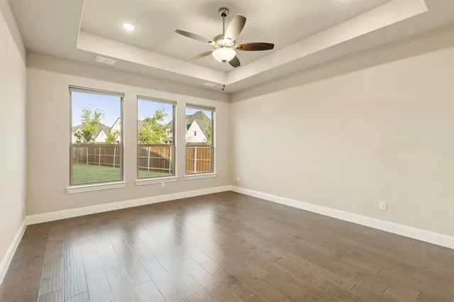 an empty room with wooden floor and ceiling fan