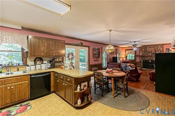 a kitchen with a stove a sink dishwasher a dining table and chairs with wooden floor