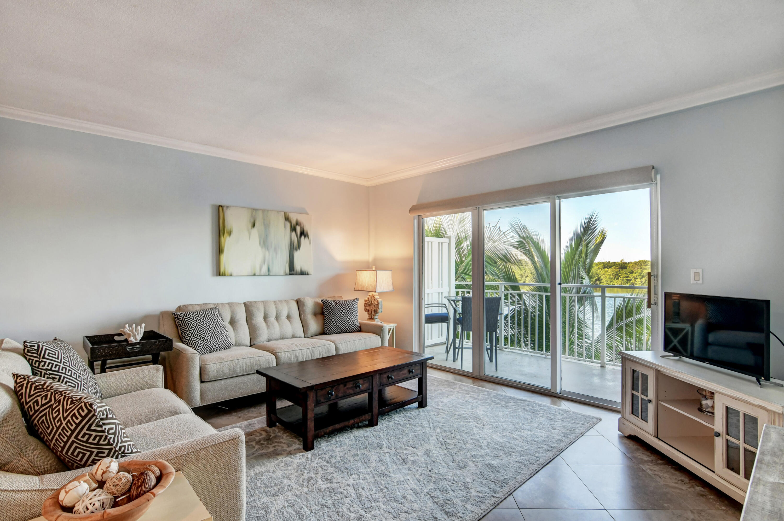 6520 North Ocean Boulevard, Unit 240 Ocean Ridge, FL 33435 - Photo 5 of 29 a living room with furniture a flat screen tv and a floor to ceiling window