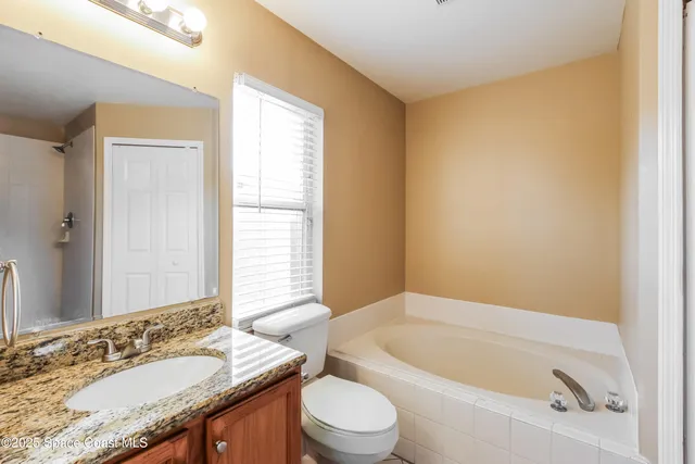 a bathroom with a granite countertop sink a toilet a mirror and bathtub