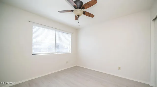 an empty room with a window and a fan