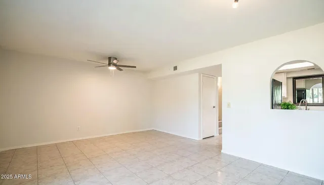 an empty room with chandelier fan and windows