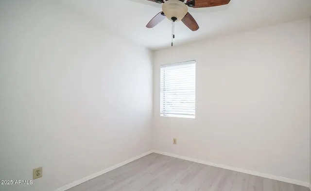 an empty room with chandelier fan and windows