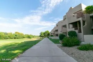 a view of a white house next to a yard with big trees
