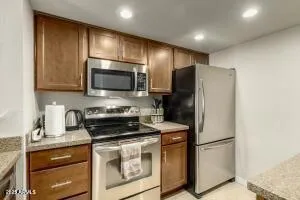 a kitchen with stainless steel appliances granite countertop a refrigerator a stove a sink and a microwave