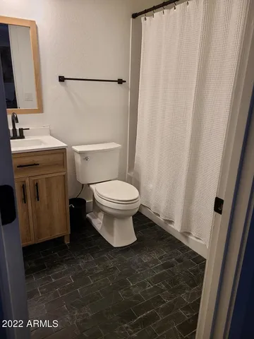 a bathroom with a granite countertop sink a toilet and a mirror