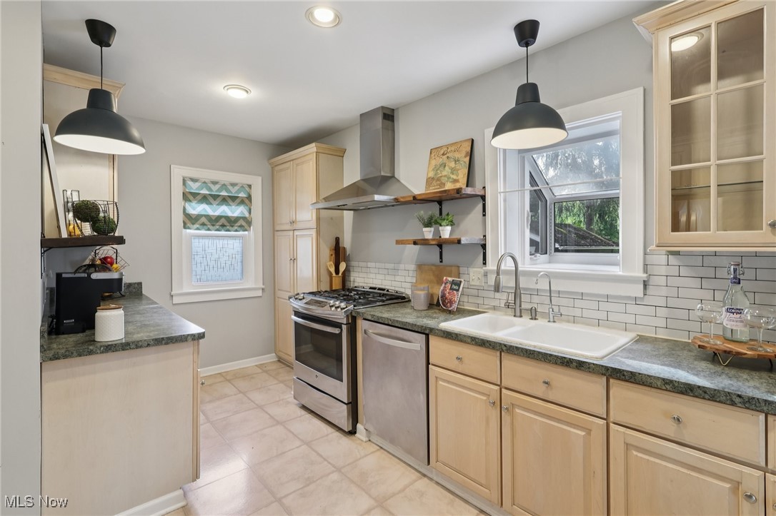 2482 Princeton Road Cleveland, OH 44118 - Photo 10 of 32 Kitchen with dark countertops, wall chimney exhaust hood, appliances with stainless steel finishes, hanging light fixtures, and decorative backsplash