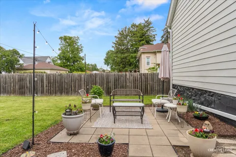 a backyard of a house with dining table and chairs