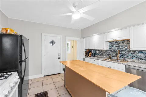 a large kitchen with stainless steel appliances kitchen island granite countertop a refrigerator and a sink