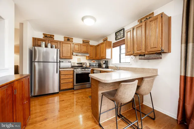 a kitchen with stainless steel appliances granite countertop a refrigerator a stove a sink dishwasher and a microwave with wooden floor