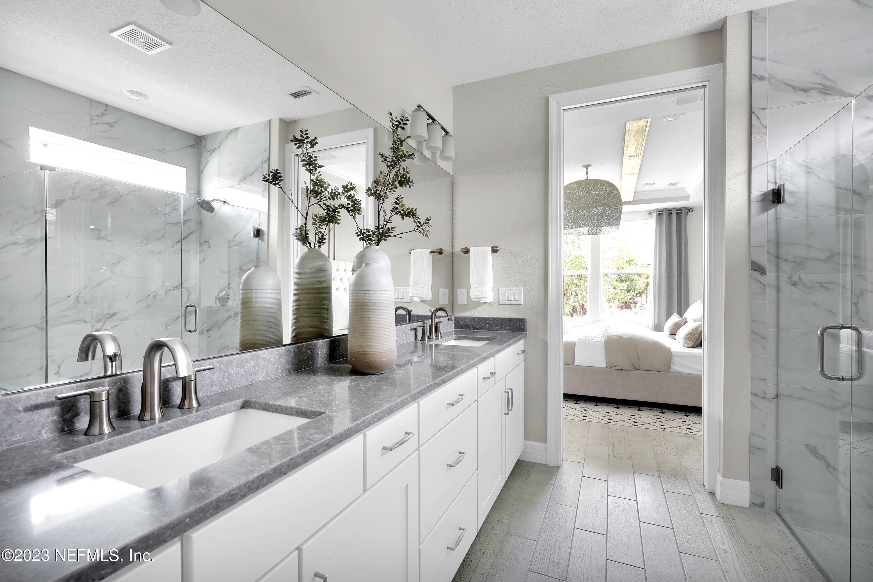 384 Del Webb Parkway Yulee, FL 32097 - Photo 19 of 35 a spacious en suite bathroom with a double vanity sink a large mirror and a shower