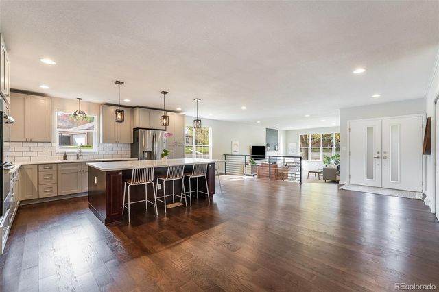 a dining hall with stainless steel appliances a dining table chairs and kitchen view