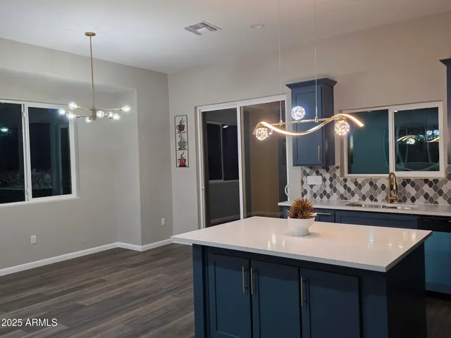 a kitchen with refrigerator a island and a wooden floor