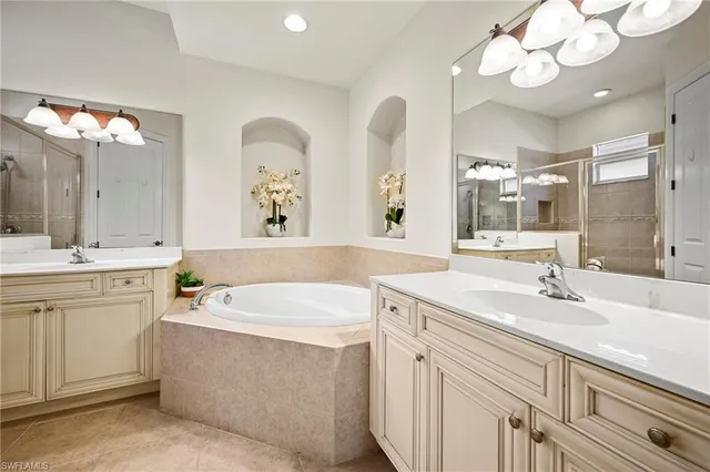 a bathroom with a double vanity sink mirror and bathtub