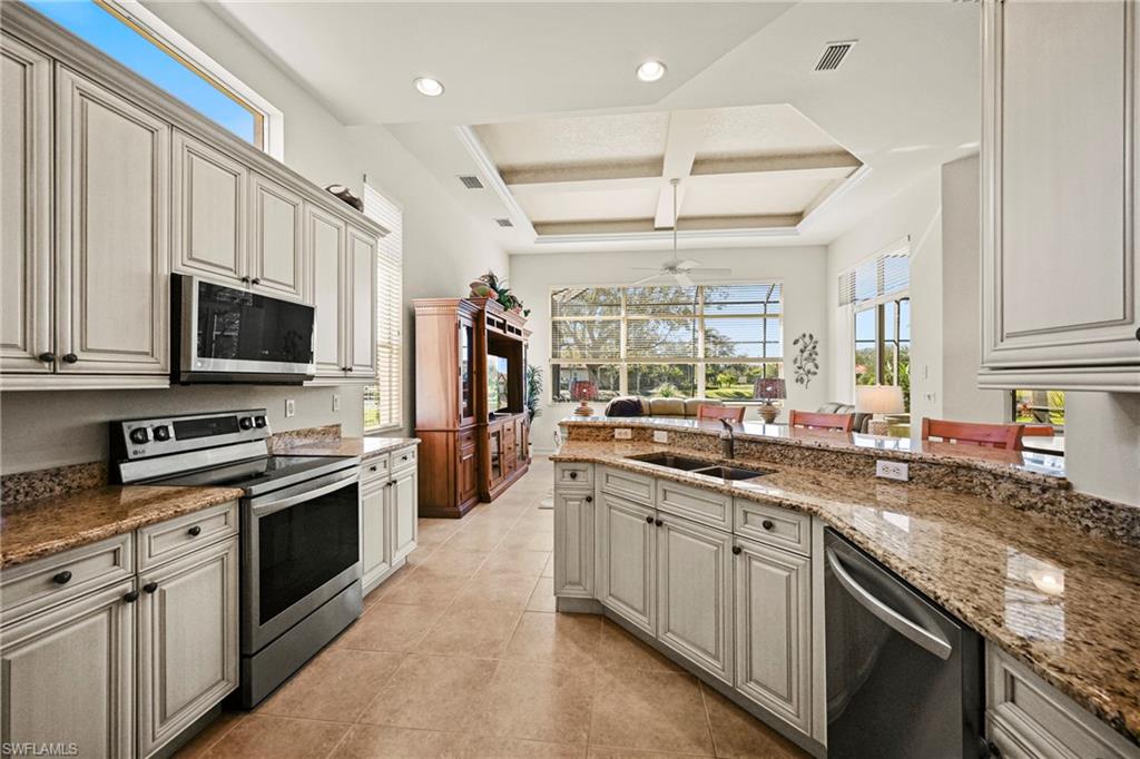 12592 Grandezza Circle Estero, FL 33928 - Photo 4 of 40 a kitchen with stainless steel appliances granite countertop a stove top oven a sink dishwasher a refrigerator and a microwave
