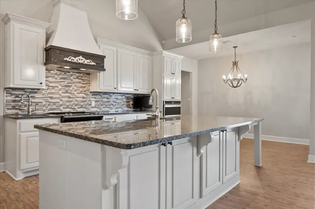 a kitchen with stainless steel appliances granite countertop a sink a stove and a wooden floors