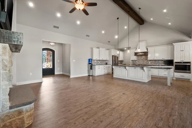 a large white kitchen with lots of counter space a sink appliances and cabinets