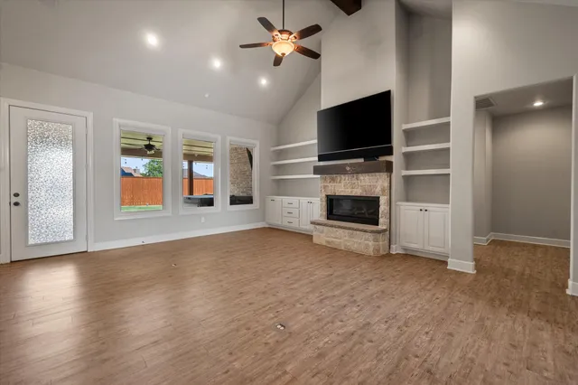 an empty room with windows fireplace and a flat screen tv