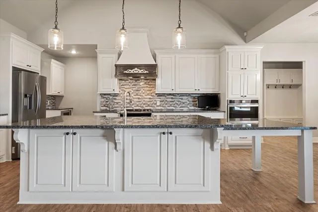 a kitchen with stainless steel appliances granite countertop a stove a sink dishwasher and a refrigerator with wooden floor