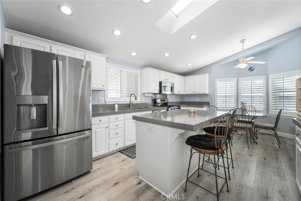 16222 Monterey Lane, Unit 371 Huntington Beach, CA 92649 - Photo 12 of 70 a kitchen with stainless steel appliances granite countertop a stove a sink a refrigerator and white cabinets with wooden floor