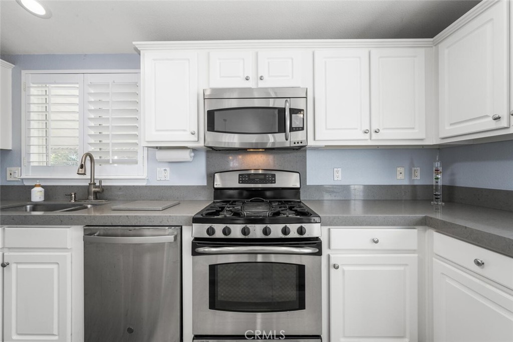 16222 Monterey Lane, Unit 371 Huntington Beach, CA 92649 - Photo 13 of 70 a kitchen with granite countertop white cabinets and white stainless steel appliances