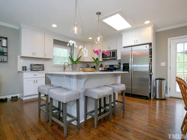 a kitchen with stainless steel appliances granite countertop a refrigerator a stove top oven a sink dishwasher and white cabinets with wooden floor