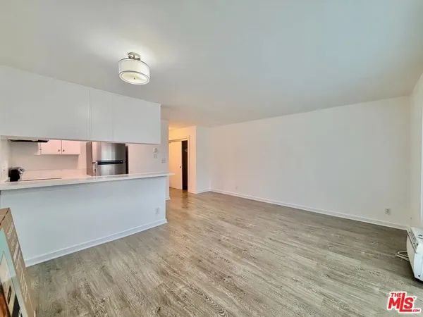 a view of kitchen and empty room with wooden floor