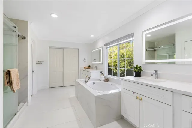 a bathroom with a double vanity sink a mirror and a bathtub