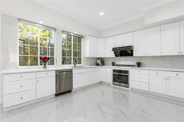 a kitchen with white cabinets stainless steel appliances and window