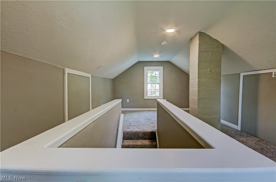 14507 Glencliffe Road Cleveland, OH 44111 - Photo 26 of 31 Staircase featuring vaulted ceiling, a textured ceiling, and dark carpet