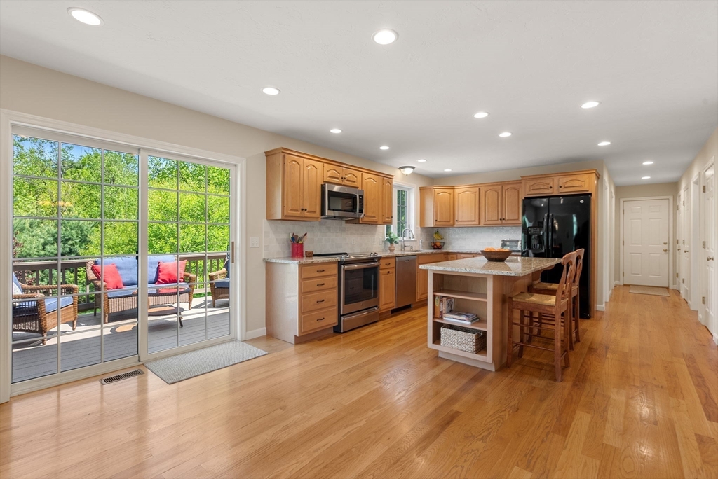 7 Brook Hill Road Sturbridge, MA 01518 - Photo 16 of 41 a kitchen with stainless steel appliances kitchen island granite countertop a stove top oven a sink dishwasher a dining table and chairs with wooden floor