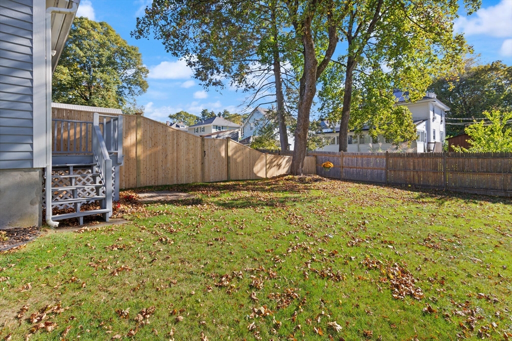 35 Roosevelt Street, Unit 35 Maynard, MA 01754 - Photo 5 of 39 a view of backyard with large tree and wooden fence