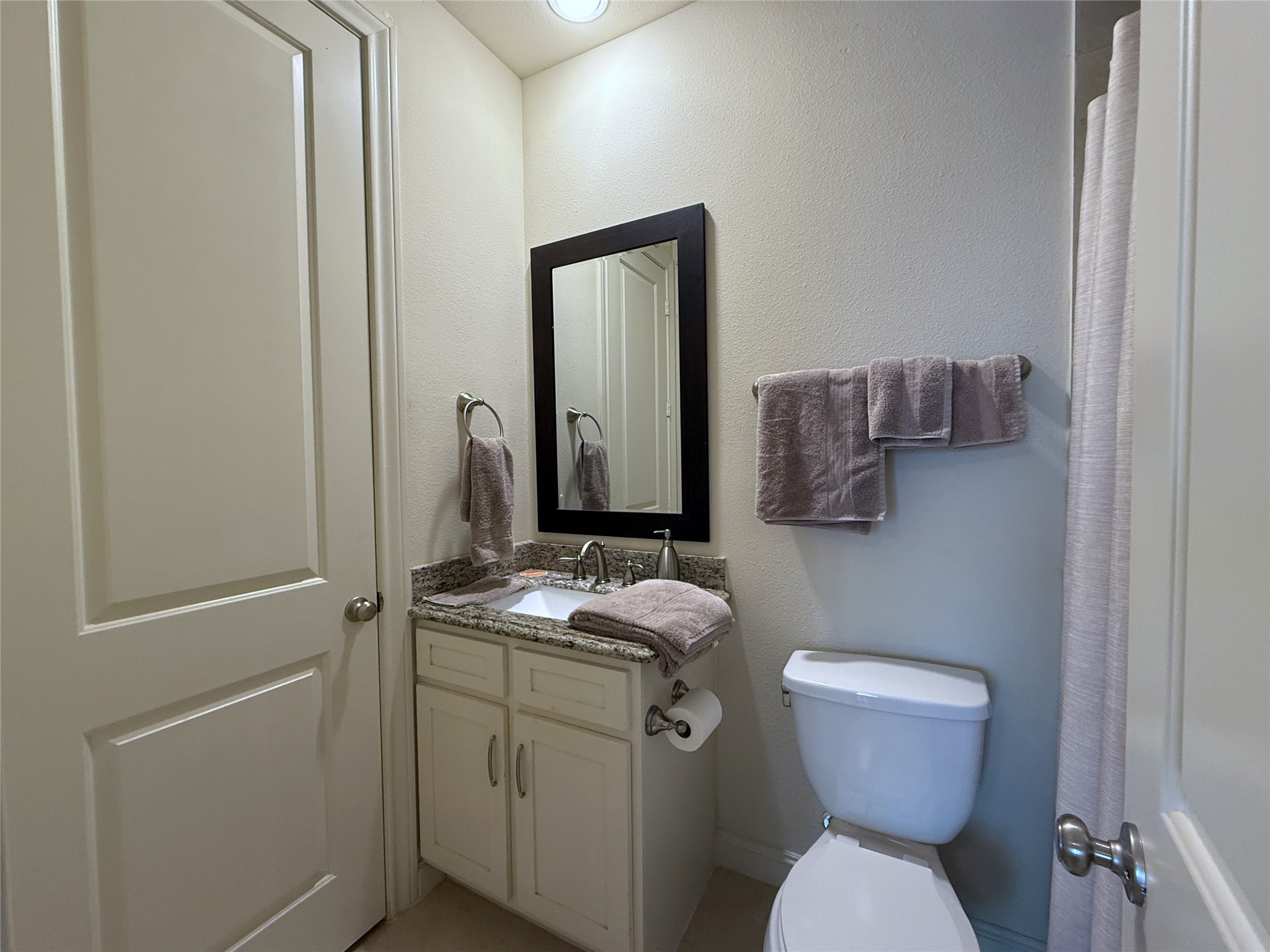 705 Delano Street Houston, TX 77003 - Photo 4 of 28 a bathroom with a granite countertop toilet sink and mirror