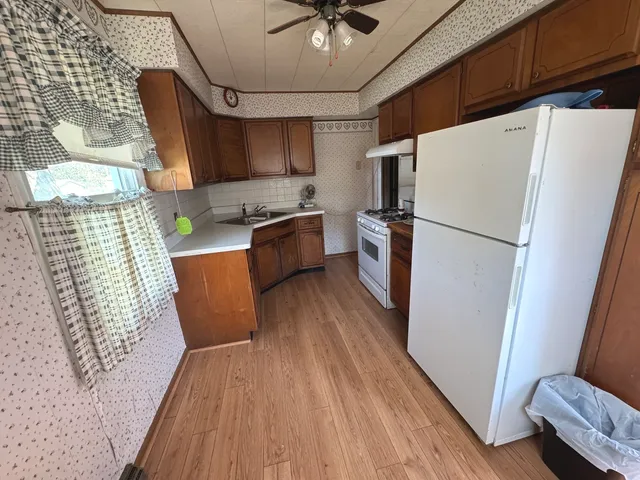 a kitchen with stainless steel appliances a refrigerator a sink a stove a microwave oven with wooden floor