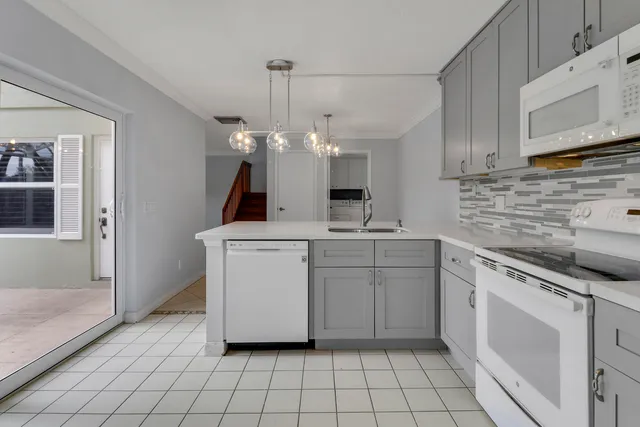 a kitchen with white cabinets a sink dishwasher and a stove with wooden floor