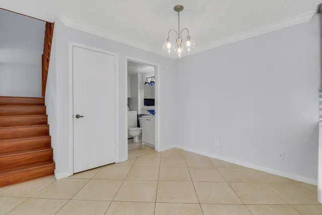 a view of an empty room with stairs and chandelier