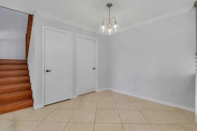 a view of an empty room with stairs and chandelier