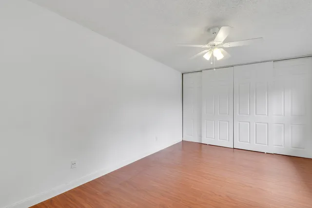 an empty room with wooden floor and fan