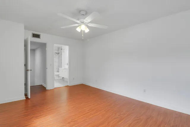 an empty room with wooden floor and fan