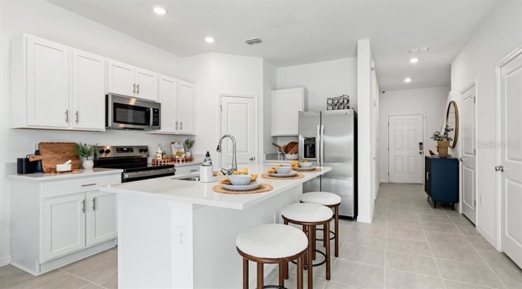 13134 Stable Place Parrish, FL 34219 - Photo 5 of 28 a kitchen with stainless steel appliances a stove a sink a microwave a refrigerator and cabinets